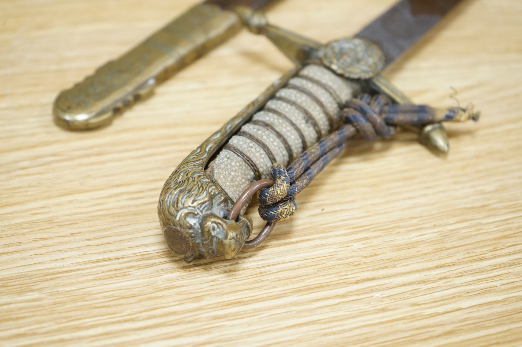A post 1902 Naval Officer’s Dirk, the regulation blade with crowned fouled anchor, regulation hilt with remains of bullion dress knot in its leather scabbard with brass mounts, locket engraved with owners initials; RSA